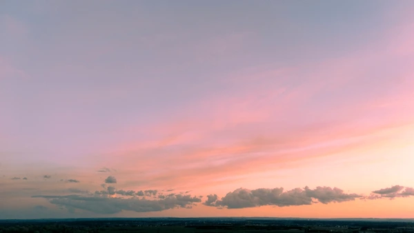 Soft evening light transitioning through warm amber tones into a calm dusk atmosphere with gentle horizon silhouettes